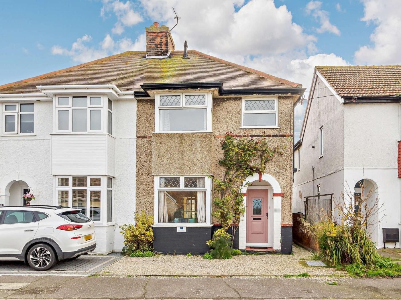 A two-story residential building with a garage, a front door, and a small garden area.