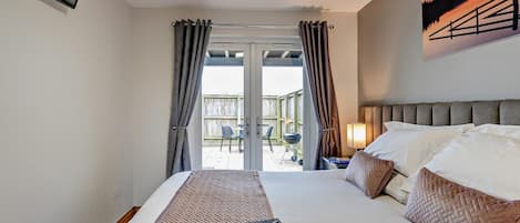 A hotel room with a bed, a TV mounted on the wall, and a view of the outside.