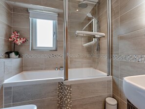 Un bagno moderno con doccia vetrata, una vasca da bagno ampia e il water.