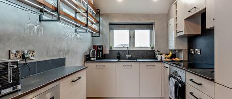 Eine moderne Küche mit Backofen, Kaffeemaschine und einem Fenster über der Spüle.