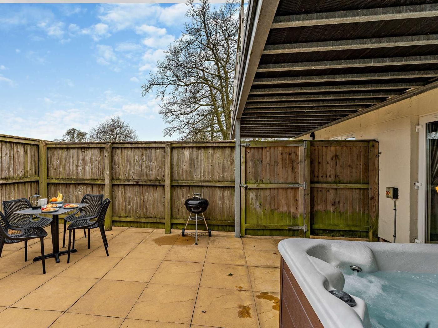 Un'area patio con tavolo e sedie, un barbecue e una vasca idromassaggio.