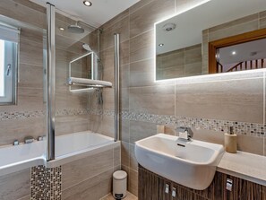 Un bagno moderno con cabina doccia in vetro, lavabo sospeso e specchio sopra il lavabo.
