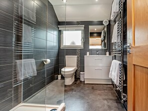 Un bagno moderno con box doccia in vetro, un water, un lavandino con specchio e un porta asciugamani.