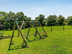 A swing set in a grassy field with trees in the background. - 2 Bed in Callington (oc-kates) (South Hill)