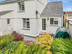 Ein zweistöckiges Haus mit weißer Fassade, zahlreichen Fenstern und einer Satellitenschüssel.
