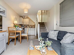 Ein kompakter Wohnraum mit Essbereich, Küche, Treppe und einer Couch.