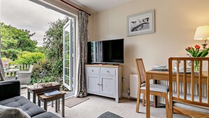 Een moderne woonkamer met een televisie, eettafel en bank.