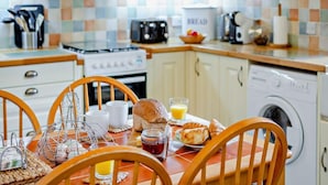 A kitchen with a dining table, chairs, a toaster, a kettle, a bread box, and a washing machine. - 2 Bed in Callington (oc-tyler) (South Hill)