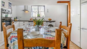 Una cocina compacta con armarios blancos, horno empotrado y una ventana con cortinas.