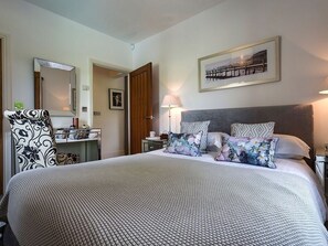 A hotel room with a large bed, a desk with a chair, a mirror, a lamp, and a framed picture on the wall. - 1 Bed in Coniston (oc-lcc50) (Coniston)