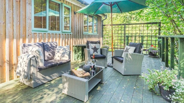 A wooden deck with wicker furniture and a green umbrella. - 1 Bed in Harrogate (oc-93258) (Thornthwaite)
