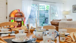 A dining area with a jukebox, a table set with tea cups, teapots, and a honey jar. - 1 Bed in Harrogate (oc-93258) (Thornthwaite)