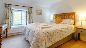 A bedroom with a bed, a window with curtains, a bedside table with a lamp, and a radiator. - 2 Bed in Ashford In The Water (oc-85823) (Ashford in the Water)