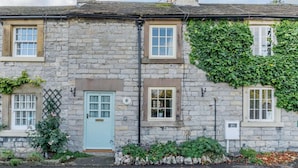 A stone building with a light blue door, windows, and a chimney. - 2 Bed in Ashford In The Water (oc-85823) (Ashford in the Water)
