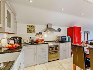 A modern kitchen with white cabinets, a red refrigerator, a stove, and a microwave. - 2 Bed in Fowey (oc-76446) (Golant)