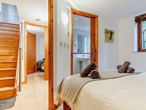 Ein Schlafzimmer mit einem Bett, ein Badezimmer mit Waschbecken und Spiegel sowie eine Holztreppe.