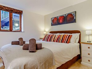 Quarto de hotel com cama, mesa de cabeceira, luminária, janela com vista para uma piscina e arte na parede.