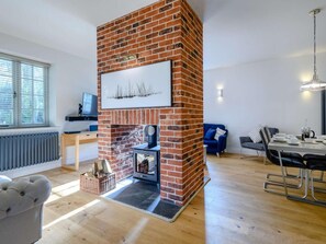A modern living room with a brick fireplace, a dining area, and a sofa. - 2 Bed in Norwich (oc-77807) (Ashmanhaugh)