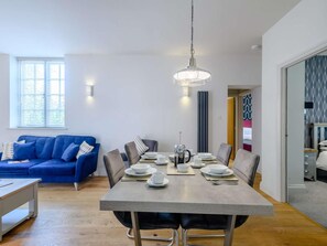 A dining area with a table set for four, a blue sofa, and a modern pendant light. - 2 Bed in Norwich (oc-77807) (Ashmanhaugh)