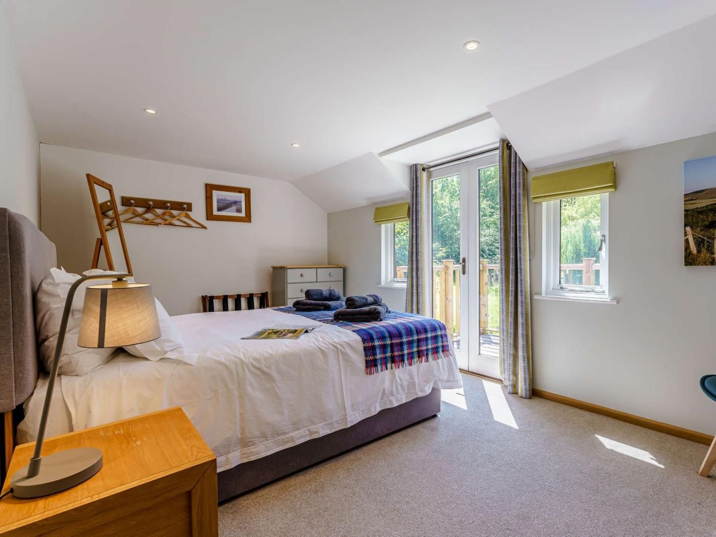 A bedroom with a bed, bedside table, lamp, and a view of the outdoors through a sliding door.