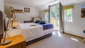 A bedroom with a bed, bedside table, lamp, and a view of the outdoors through a sliding door. - 2 Bed in Uckfield (oc-80504) (Framfield)