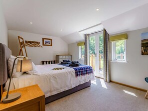 A bedroom with a bed, bedside table, lamp, and a view of the outdoors through a sliding door. - 2 Bed in Uckfield (oc-80504) (Framfield)
