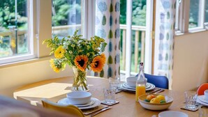 A dining table set with plates, glasses, a vase of flowers, and a bowl of fruit. - 2 Bed in Uckfield (oc-80504) (Framfield)