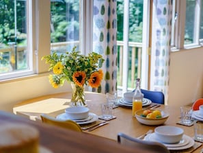 A dining table set with plates, glasses, a vase of flowers, and a bowl of fruit. - 2 Bed in Uckfield (oc-80504) (Framfield)