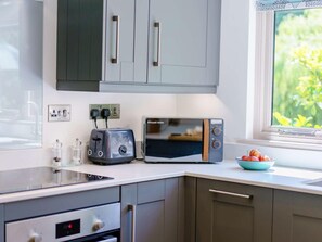 A modern kitchen with a built-in microwave, toaster, and a window with a view of greenery. - 2 Bed in Uckfield (oc-80504) (Framfield)