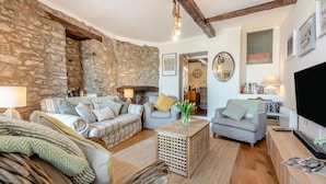 A cozy living room with stone walls, a fireplace, and a television. - 3 Bed in Tenby (oc-fb225) (Tenby)