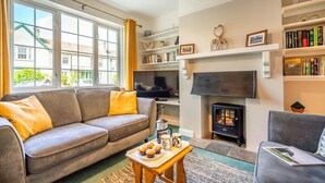 A cozy living room with a sofa, a television, a fireplace, and a bookshelf. - 3 Bed in Keswick (oc-sz316) (Keswick)