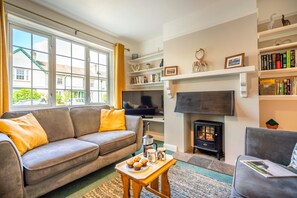 A cozy living room with a sofa, a television, a fireplace, and a bookshelf. - 3 Bed in Keswick (oc-sz316) (Keswick)