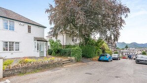 A residential street with houses, parked cars, and a tree. - 3 Bed in Keswick (oc-sz316) (Keswick)