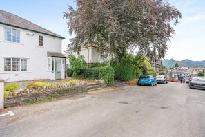 A residential street with houses, parked cars, and a tree. - 3 Bed in Keswick (oc-sz316) (Keswick)