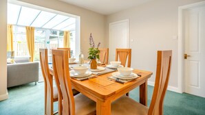 A dining area with a wooden table set for four, surrounded by chairs, with a window providing natural light. - 3 Bed in Keswick (oc-sz316) (Keswick)