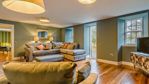 Una sala de estar con un sofá modular, un televisor y un ventanal grande.