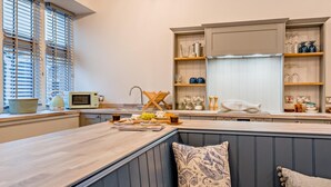Una cocina moderna con encimera de madera, microondas integrado y un fregadero.