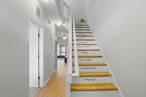 A staircase with wooden steps and white walls, leading to a room with a ceiling fan and a view of a window. - Coral Cay 4BR Vacation Home,Close to Disney (Kissimmee)