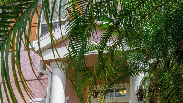 Un edificio con una facciata rosa, colonne bianche e una porta marrone.