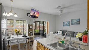 Una cucina moderna con zona pranzo, ventilatore a soffitto e televisore a parete.