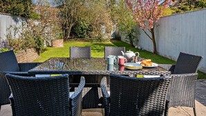 A patio with wicker furniture, a table set with a teapot, cups, and a plate of food. - 3 Bed in Brockenhurst (oc-nfl92) (Brockenhurst)