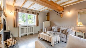 Ein gemütliches Wohnzimmer mit einem Karomuster-Sofa, einem Kamin und einer Dekoration aus Hirschgeweihen.