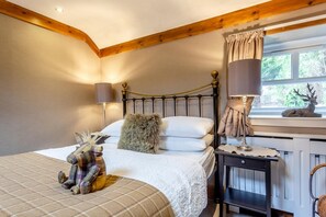 A bedroom with a bed, bedside lamps, a nightstand, a window with a view of greenery, and a deer decoration. - 1 Bed in Callander (oc-pe173) (Strathyre)