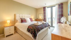 A hotel room with a bed, bedside table, nightstand, and a view of the outdoors.