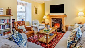 Ein Wohnzimmer mit Kamin, Fernseher, Bücherregal und Sofa.