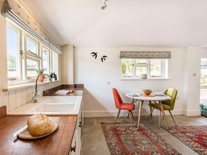 A kitchen with a wooden countertop, a sink, and a dining area with a table and chairs. - 1 Bed in Ventnor (oc-85978) (Chale Green)