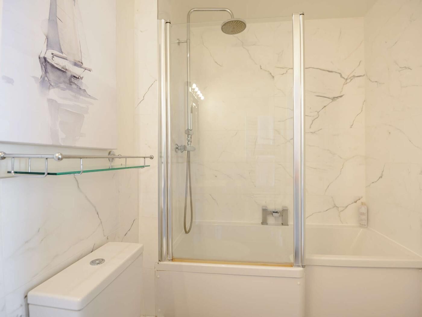 Une salle de bain avec une douche à parois de verre, des toilettes et un mur en marbre.
