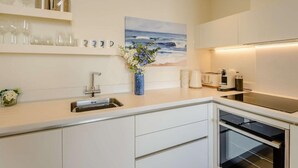 A modern kitchen with white cabinetry, a built-in oven, and a countertop with a toaster. - 1 Bed in Hythe (oc-89969) (Hythe)