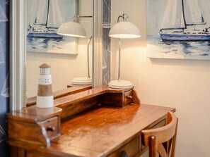 Ein Holztisch mit einem Spiegel, zwei Lampen und einem Gemälde eines Segelbootes.