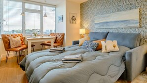 A modern bedroom with a large bed, a dining area, and a view through the window. - 1 Bed in Hythe (oc-89969) (Hythe)